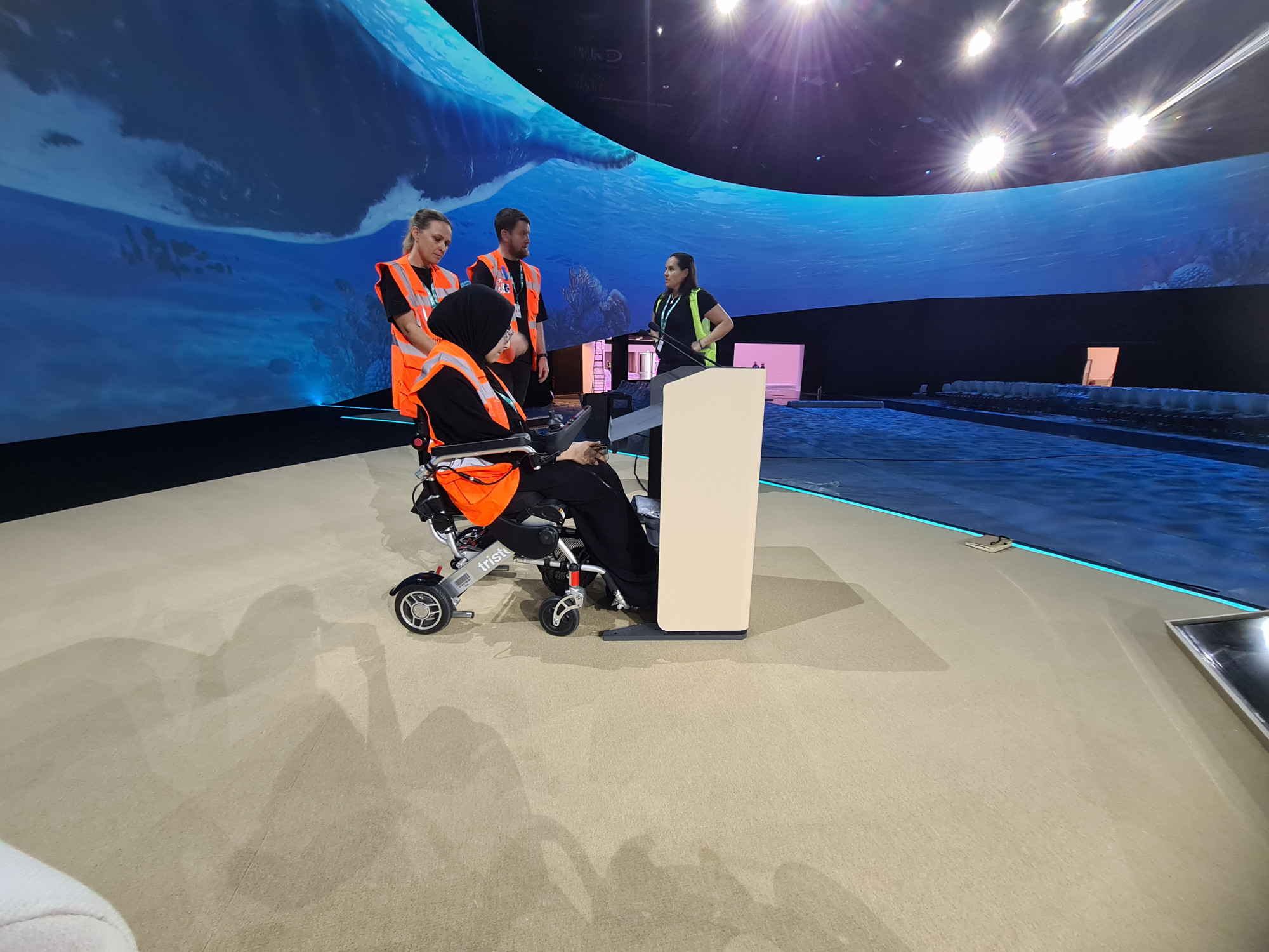 A wheelchair user testing out stage equipment with COP28 teams
