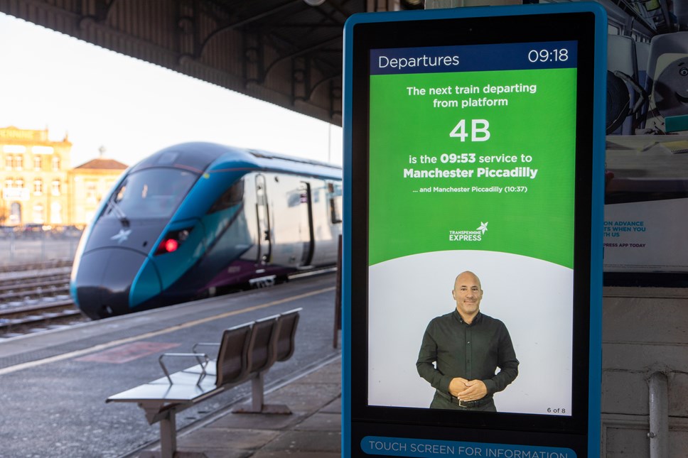A photo of British Sign Language departure boards on  next to s train waiting at a station platform