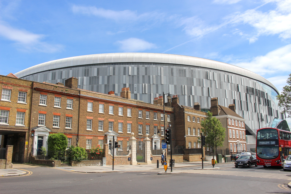 A photo of the world-leading Tottenham Hotspur stadium situated imposingly over the top of a row of terraced houses