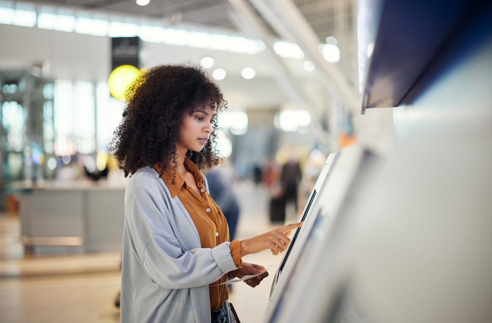 An unhappy stands alone at a self-service kiosk at an airport terminal
