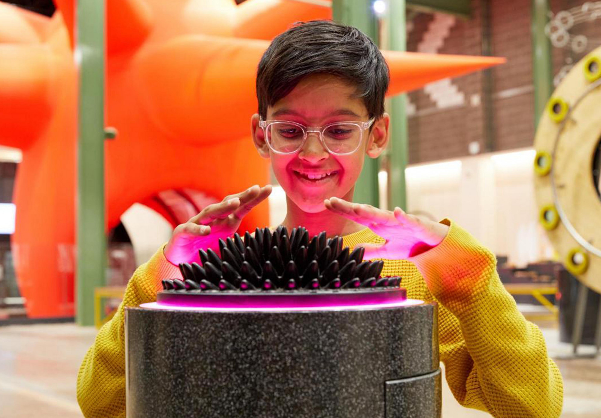 A child stands over a tactile object which emits pink light, on display at Wonderlab at The Bramall Gallery.