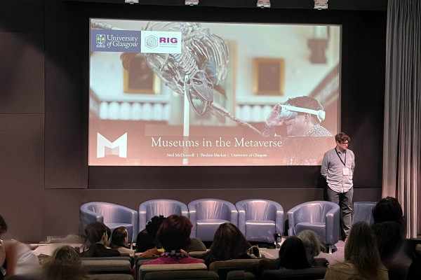 Presentation with visitors seated in front of a screen with a title Museums in the Metaverse