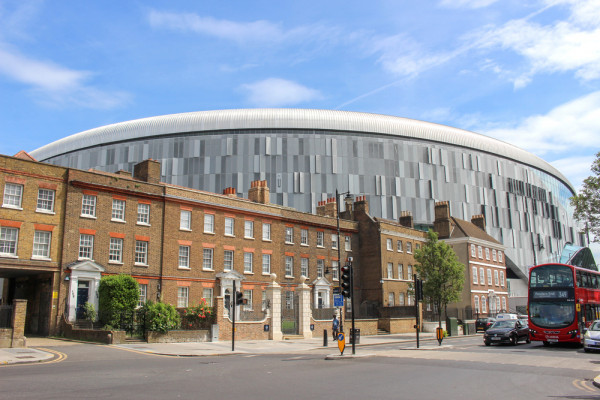 A photo of the world-leading Tottenham Hotspur stadium situated imposingly over the top of a row of terraced houses