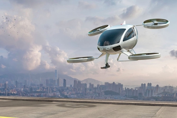 An image of an electric vertical take-off and landing (eVTOL) aircraft taking off in front of a cityscape